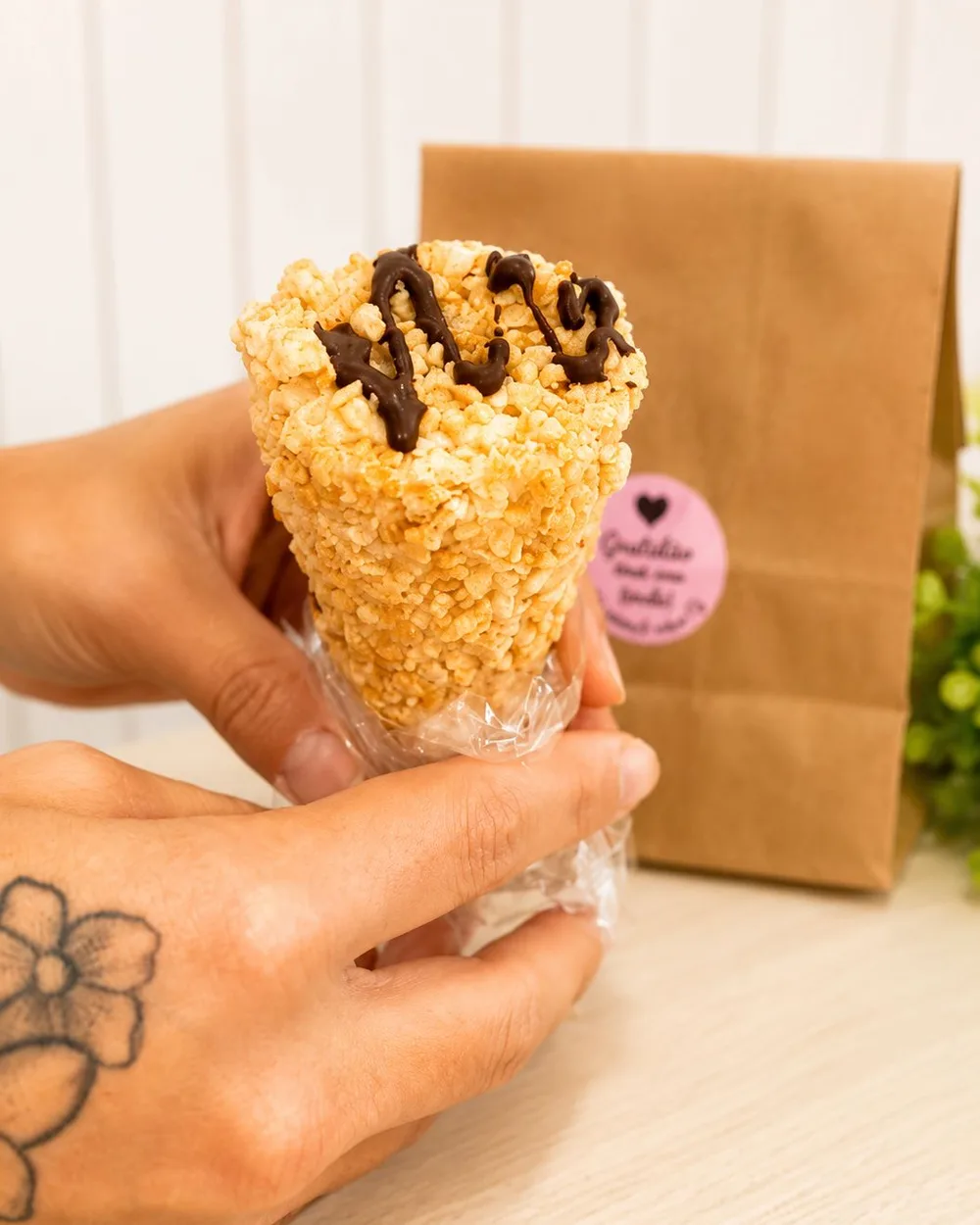 Cone trufado crocante coberto com fio de chocolate, segurado na mão